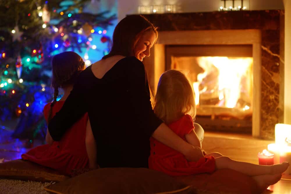 Woman with children enjoying the warmth of a nice fire at home: cozy, protected, safe, warm. The best nature has to offer.